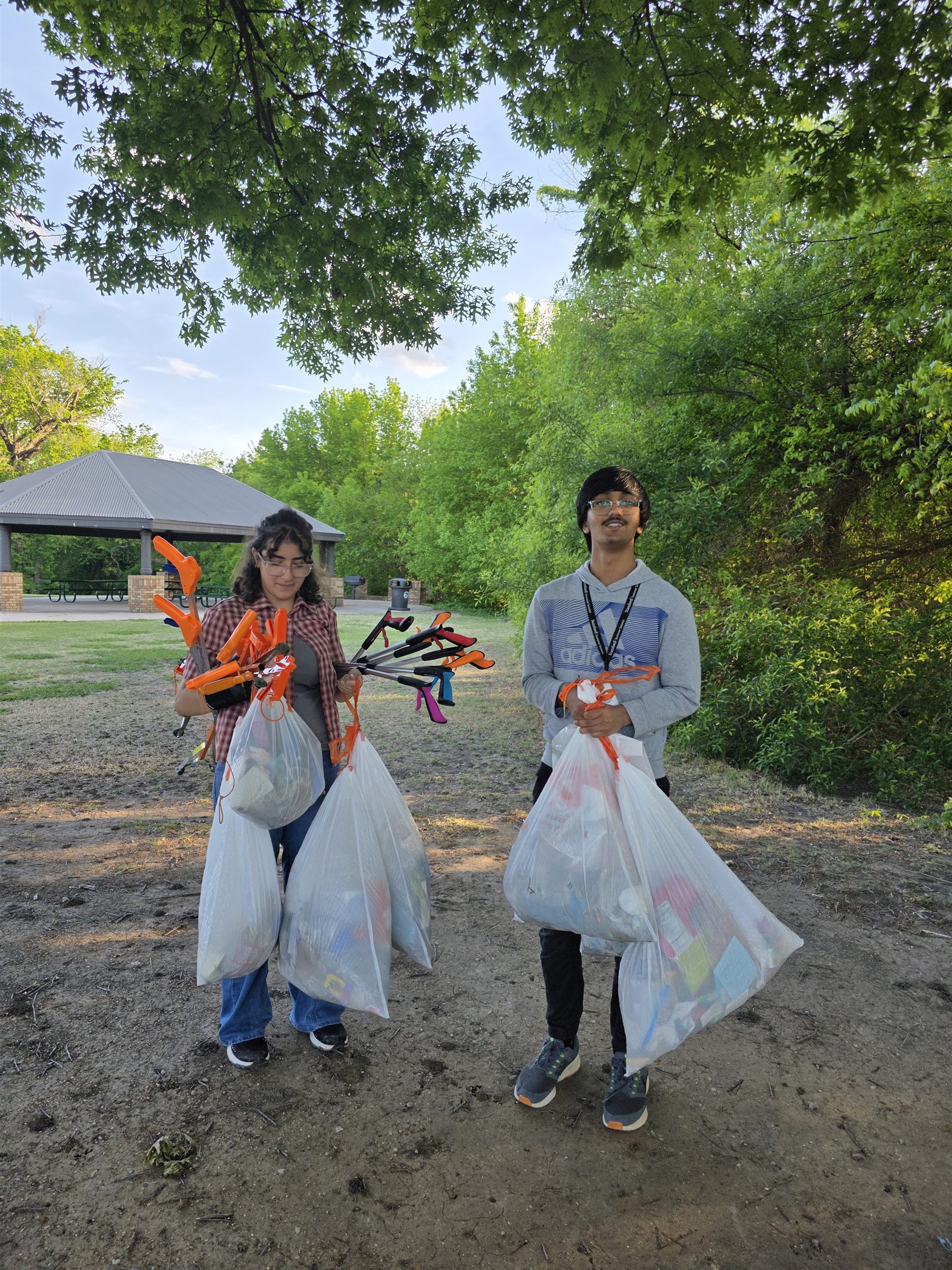 Two students holding collected trash bags at Jack Carter Park